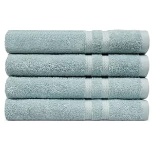 Four light blue bath towels are neatly stacked on top of each other.