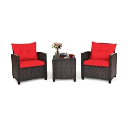 Outdoor patio set with two wicker chairs and red cushions, plus a matching wicker side table with a glass top, featuring a flower vase and a cup of tea.