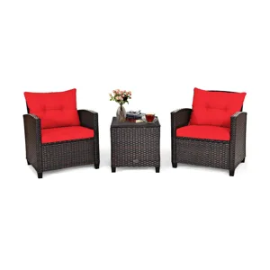 Outdoor patio set with two wicker chairs and red cushions, plus a matching wicker side table with a glass top, featuring a flower vase and a cup of tea.