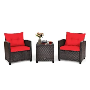 Outdoor patio set with two wicker chairs and red cushions, plus a matching wicker side table with a glass top, featuring a flower vase and a cup of tea.
