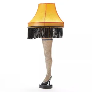 A festive lamp shaped like a woman's leg in a high heel and fishnet stocking, topped with a fringed, yellow lampshade.