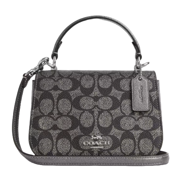 A Coach Outlet Top Handle Bag in black and gray signature jacquard pattern, featuring a detachable strap, a top handle, and a small tag with the brand name.