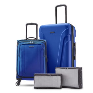 A four-piece luggage set featuring two blue suitcases, one with wheels and telescoping handle, and two grey packing cubes of different sizes.