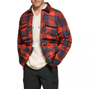 A red and navy blue checkered puffer jacket with two chest flap pockets, worn over a cream-colored hoodie.