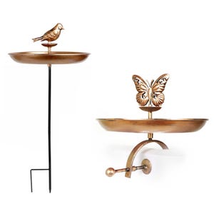 Two interchangeable bird baths feature a decorative bird on a stake and a butterfly on a wall-mounted bracket, both with circular dish designs.
