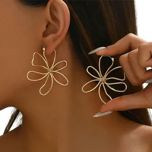 Gold-tone flower-shaped earrings with a swirling, open-petal design showcased on a person.