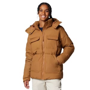 A brown Columbia insulated jacket with a hood, featuring two chest pockets and two side pockets. The jacket is worn over a dark top and paired with light-colored pants.