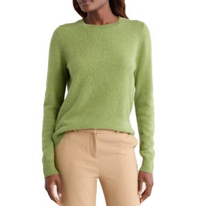 A woman is wearing a light green sweater paired with beige trousers.