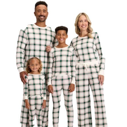 A family of four is wearing matching white and green plaid pajamas, consisting of long-sleeved tops and pants.
