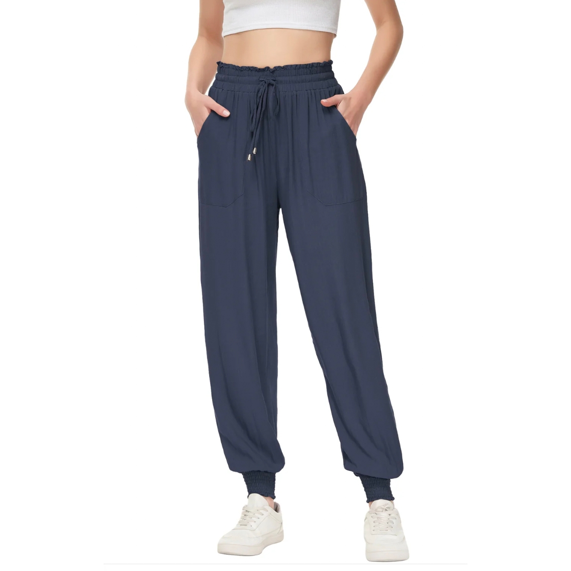 Navy blue high-waisted joggers with a drawstring waist, side pockets, and elastic cuffs at the ankles. The person is wearing white sneakers.