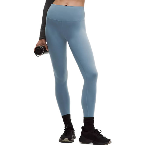 A person is wearing high-waisted blue leggings, paired with black sneakers and holding a water bottle.