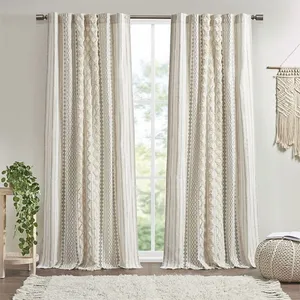 Beige and white patterned curtains hang from a rod in front of a window, with a small side table featuring a potted plant and a textured wall decoration nearby.
