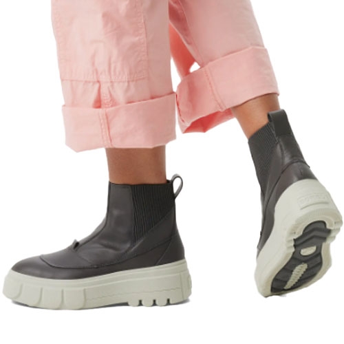 Person wearing black ankle-high boots with thick white soles, paired with rolled-up pink pants.