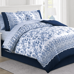 Blue and white floral-patterned bedding set with scalloped edges, including a comforter and matching pillow shams, on a bed with a white headboard.