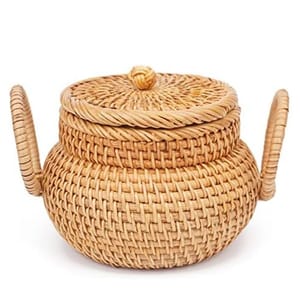 A woven rattan teapot-shaped basket with a lid and two handles, designed for decorative or storage purposes.