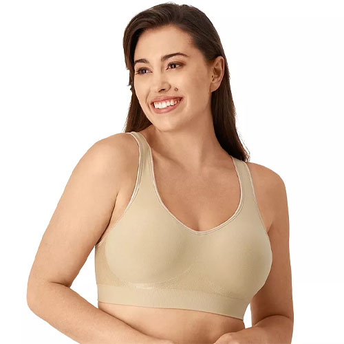 A woman is wearing a beige, seamless, wire-free bra with wide straps.