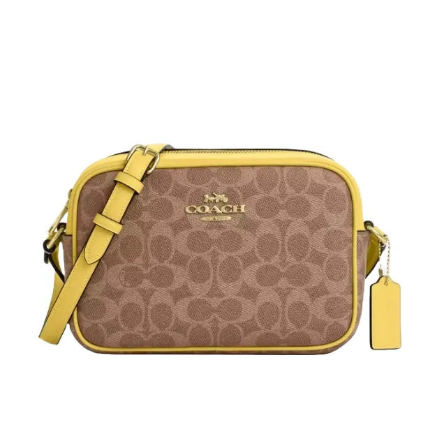 A Coach shoulder bag featuring a light brown signature pattern and yellow leather trim, with an adjustable strap and a tag.