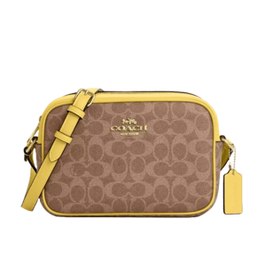 A Coach shoulder bag featuring a light brown signature pattern and yellow leather trim, with an adjustable strap and a tag.