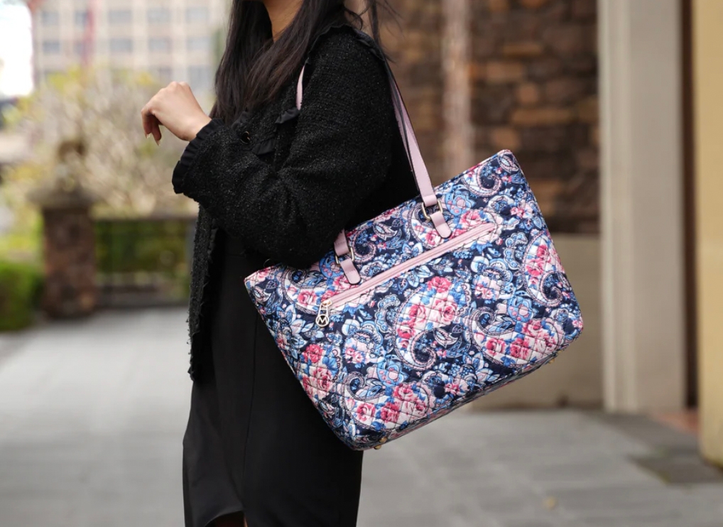A woman is carrying a patterned shoulder bag with floral and paisley designs.