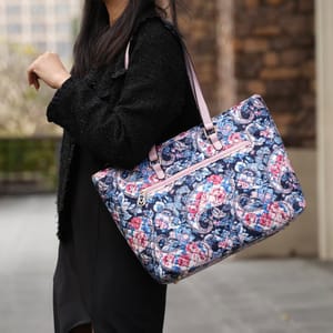 A woman is carrying a patterned shoulder bag with floral and paisley designs.
