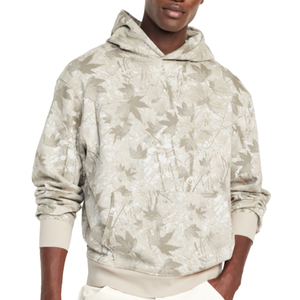 A hoodie with a beige and white leaf camouflage pattern, featuring ribbed cuffs and hem, worn with white pants.