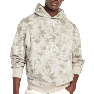 A hoodie with a beige and white leaf camouflage pattern, featuring ribbed cuffs and hem, worn with white pants.