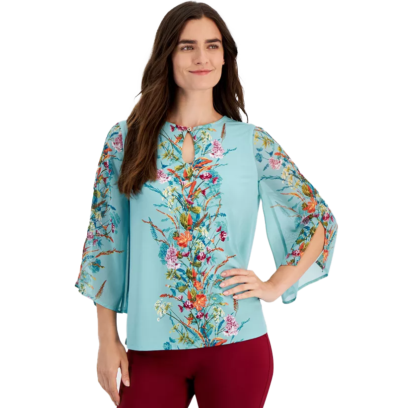 A woman models a floral-printed, light blue top with a keyhole neckline and flared three-quarter sleeves. The top is paired with burgundy pants.