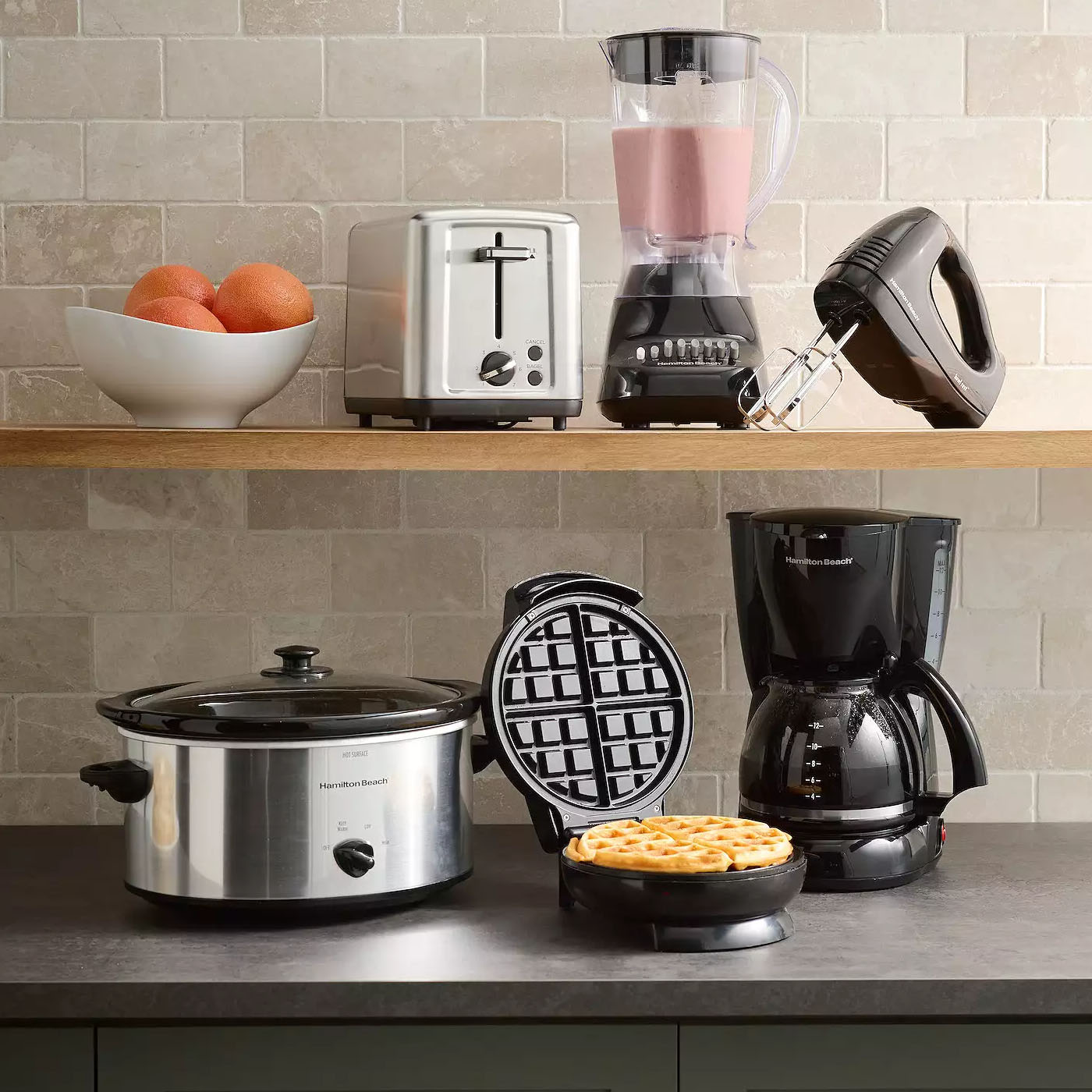 Assortment of kitchen appliances: slow cooker, toaster, blender, hand mixer, waffle maker with a cooked waffle, and a drip coffee maker.