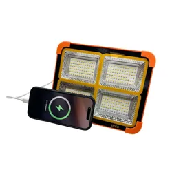A multi-LED floodlight labeled IP66 is next to a smartphone being charged via a cable. The device displays a charging status on its screen.