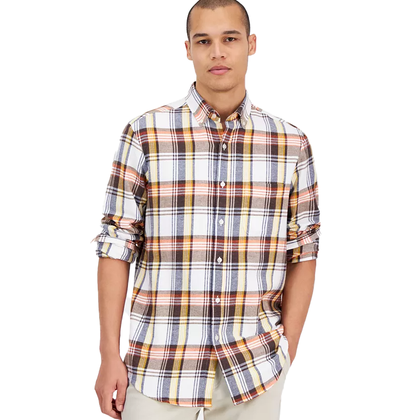 A man wearing a long-sleeve, multicolored plaid button-up shirt with rolled-up sleeves and beige pants.