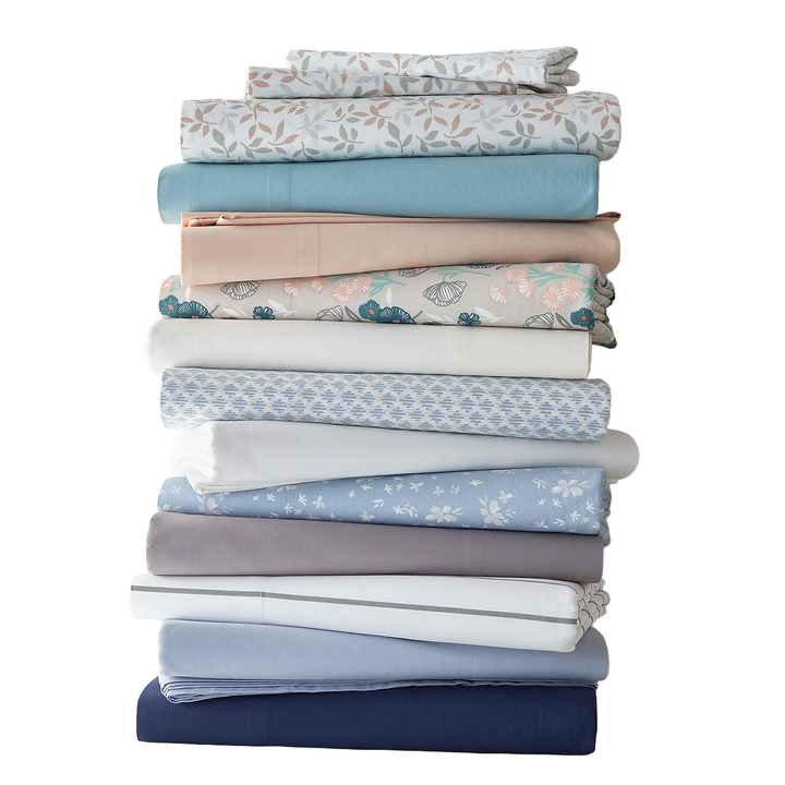 A stack of folded bed sheets in various colors and patterns, including floral and solid designs.