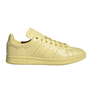 A light yellow Adidas Stan Smith sneaker with a perforated stripe design, embossed logo, and lace-up closure.