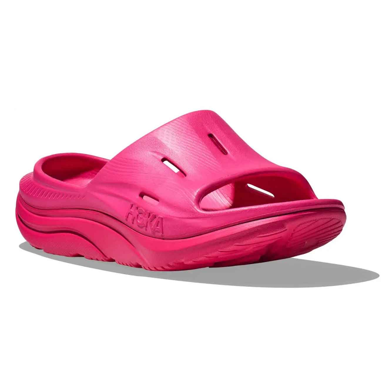 Bright pink Hoka Men's Recovery Slide featuring a thick cushioned sole, open toe design, and perforations for breathability. The brand name \“HOKA\“ is embossed on the side.