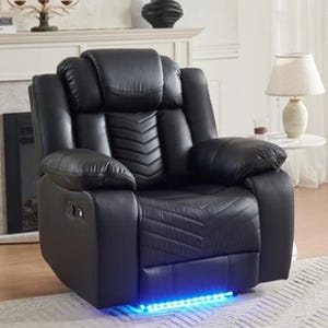 Black leather recliner with LED lighting underneath, USB charging port, and padded armrests sits in a living room with a modern design, featuring near a lamp and fireplace.