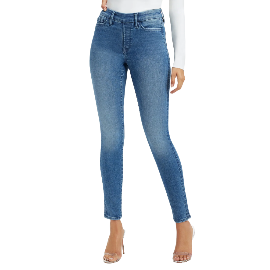 Women's blue skinny jeans with a high waist, paired with a white long-sleeve top and clear high-heeled sandals.