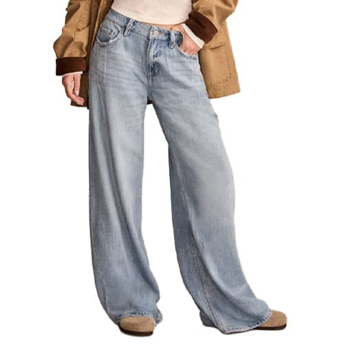 A person is wearing light blue wide-leg jeans, with a cream sweater and a brown jacket, along with tan shoes.