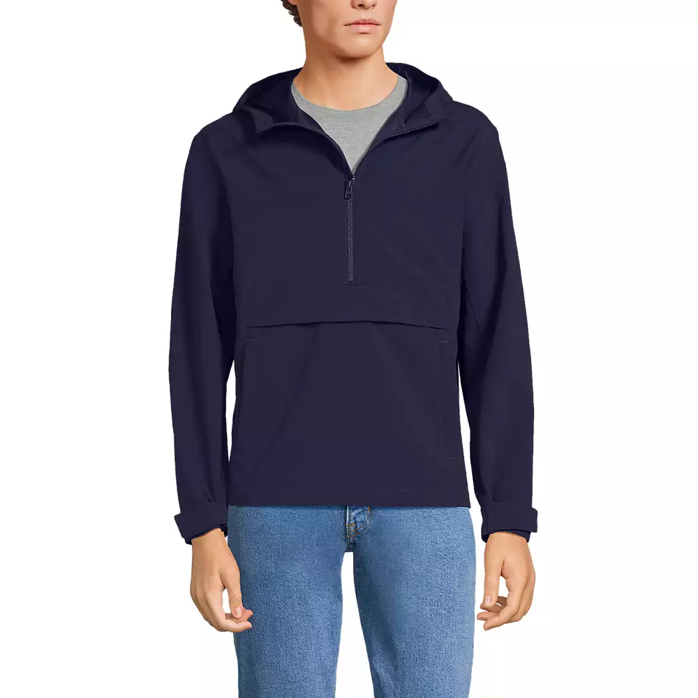 A person wearing a navy blue pullover jacket with a hood, half-zip front, and a large pocket, paired with light blue jeans.