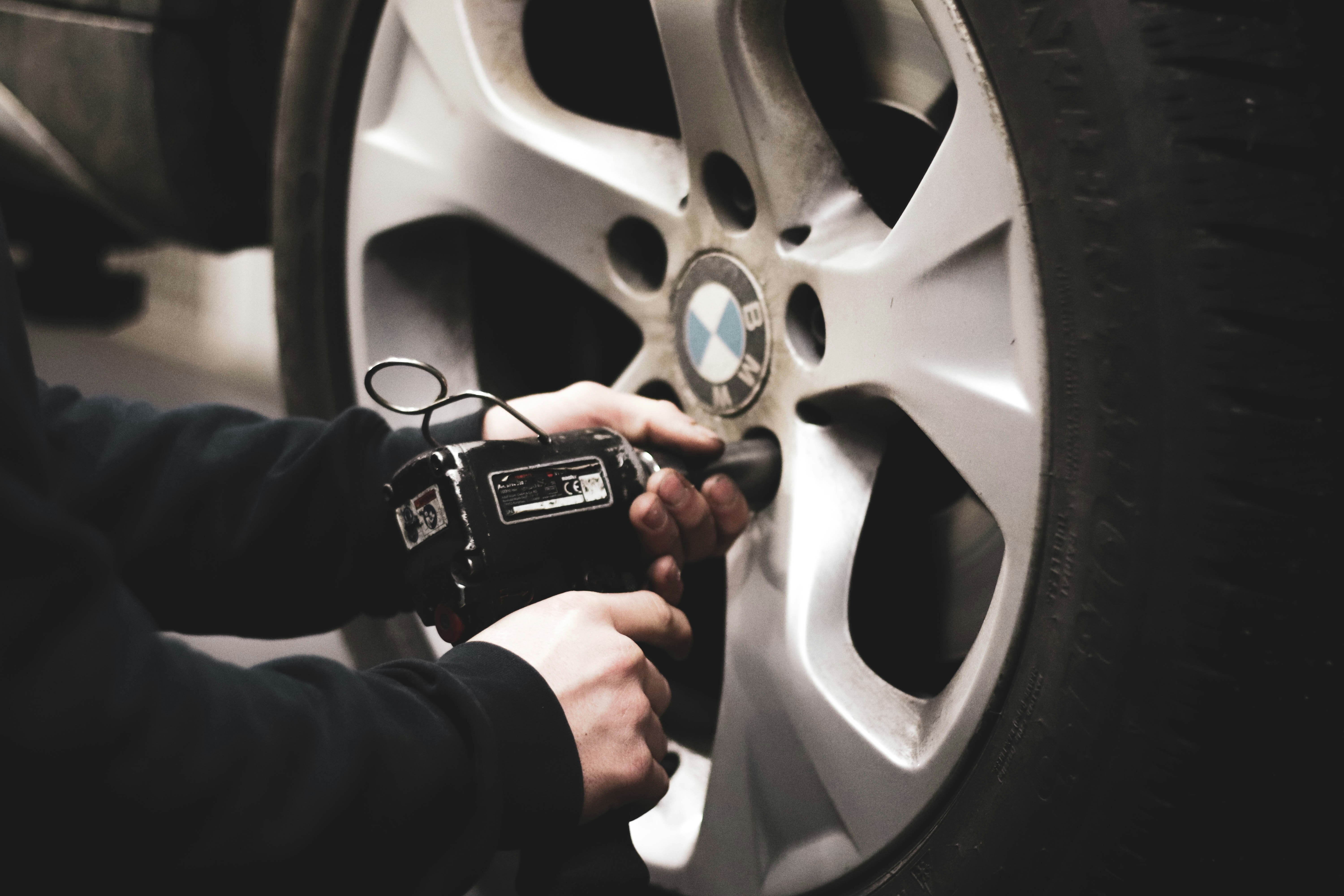 A person is using a tire pressure gauge on a BMW wheel.