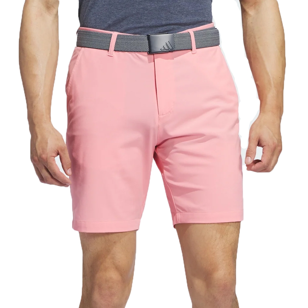 Pink Adidas golf shorts made from a smooth fabric, featuring a tailored fit with side and back pockets. The shorts are paired with a zigzag-patterned belt with an Adidas logo on the buckle.
