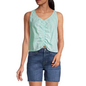 A mint green sleeveless blouse with a V-neckline and button details, paired with knee-length denim shorts.