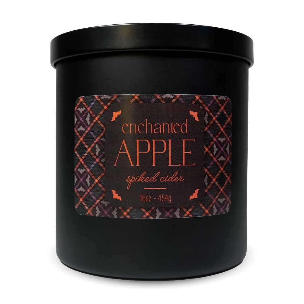 Black jar candle labeled \“enchanted APPLE spiked cider\“ with autumn-themed colors and bat decorations, 16oz / 454g.