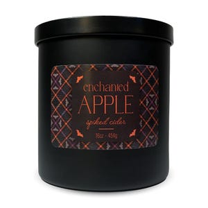 Black jar candle labeled \“enchanted APPLE spiked cider\“ with autumn-themed colors and bat decorations, 16oz / 454g.