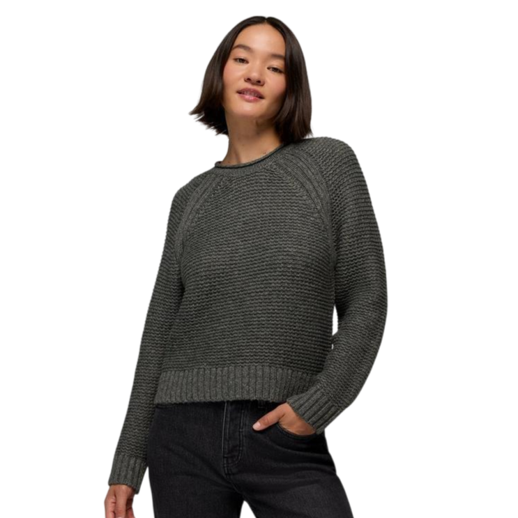A woman is wearing a textured gray knit sweater with ribbed cuffs and hem, paired with dark jeans.