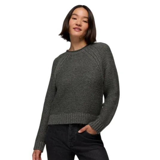 A woman is wearing a textured gray knit sweater with ribbed cuffs and hem, paired with dark jeans.