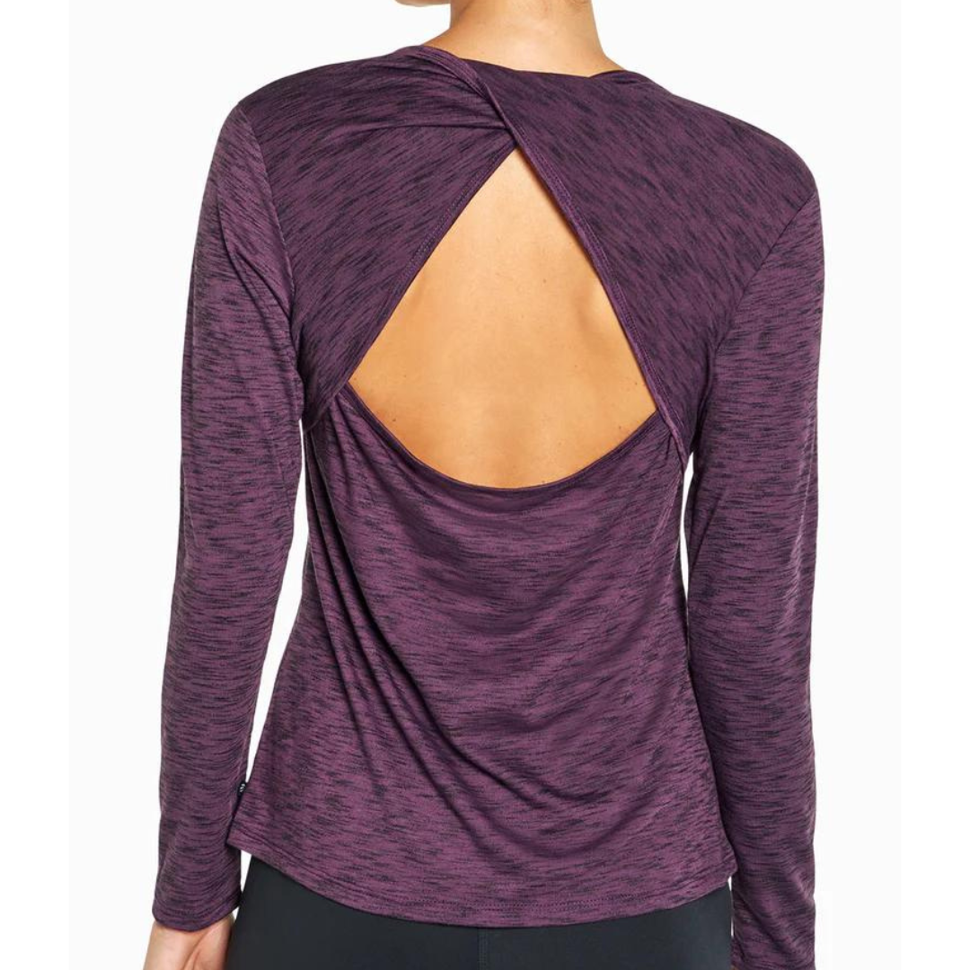 A woman wearing a purple, heathered, long sleeve top with an open back design.