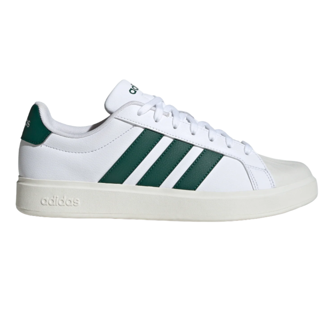 A white Adidas sneaker featuring three green stripes on the side, with \“adidas\“ branding on the heel and midsole.