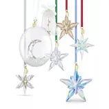 A collection of crystal holiday ornaments featuring star and bell shapes with different colored ribbons and gold year tags, showcasing intricate designs and clear, colored, and iridescent finishes.