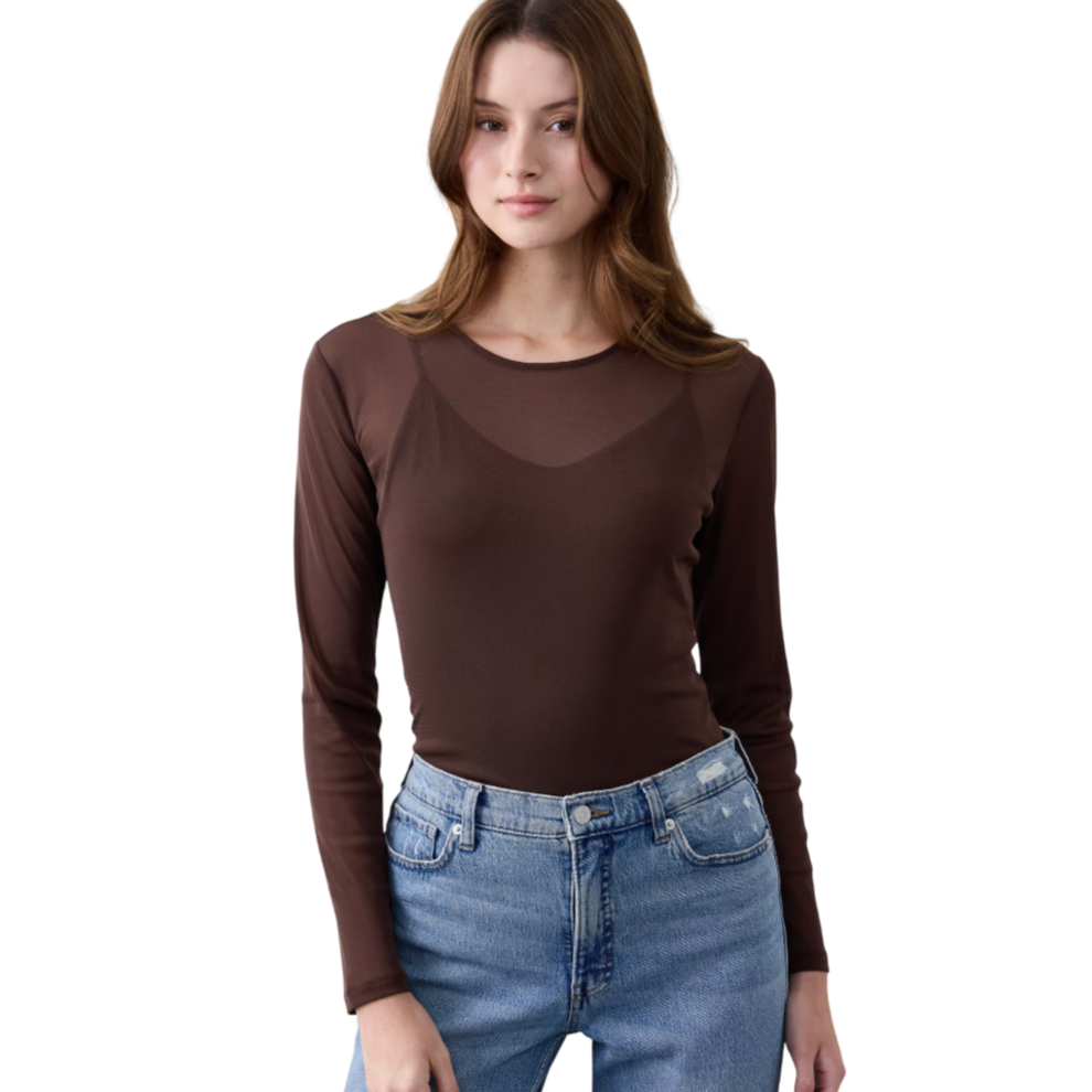 A woman is wearing a long-sleeve brown top paired with light blue high-waisted jeans.