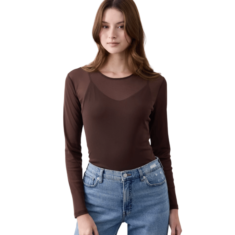 A woman is wearing a long-sleeve brown top paired with light blue high-waisted jeans.