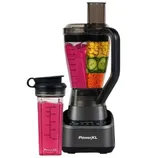 A PowerXL blender is shown with a blending jar containing layered vegetables and a personal-sized to-go cup filled with a pink smoothie, against a white brick background.